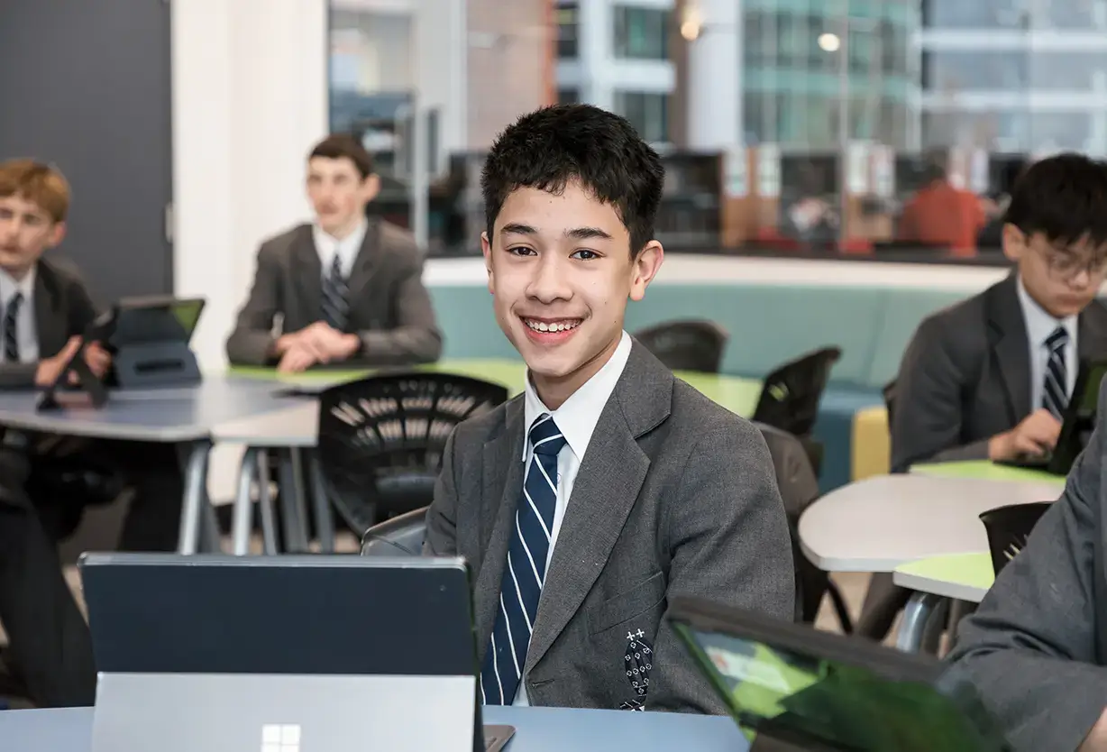 Shore School student using a laptop in a modern classroom while classmates work on digital learning activities