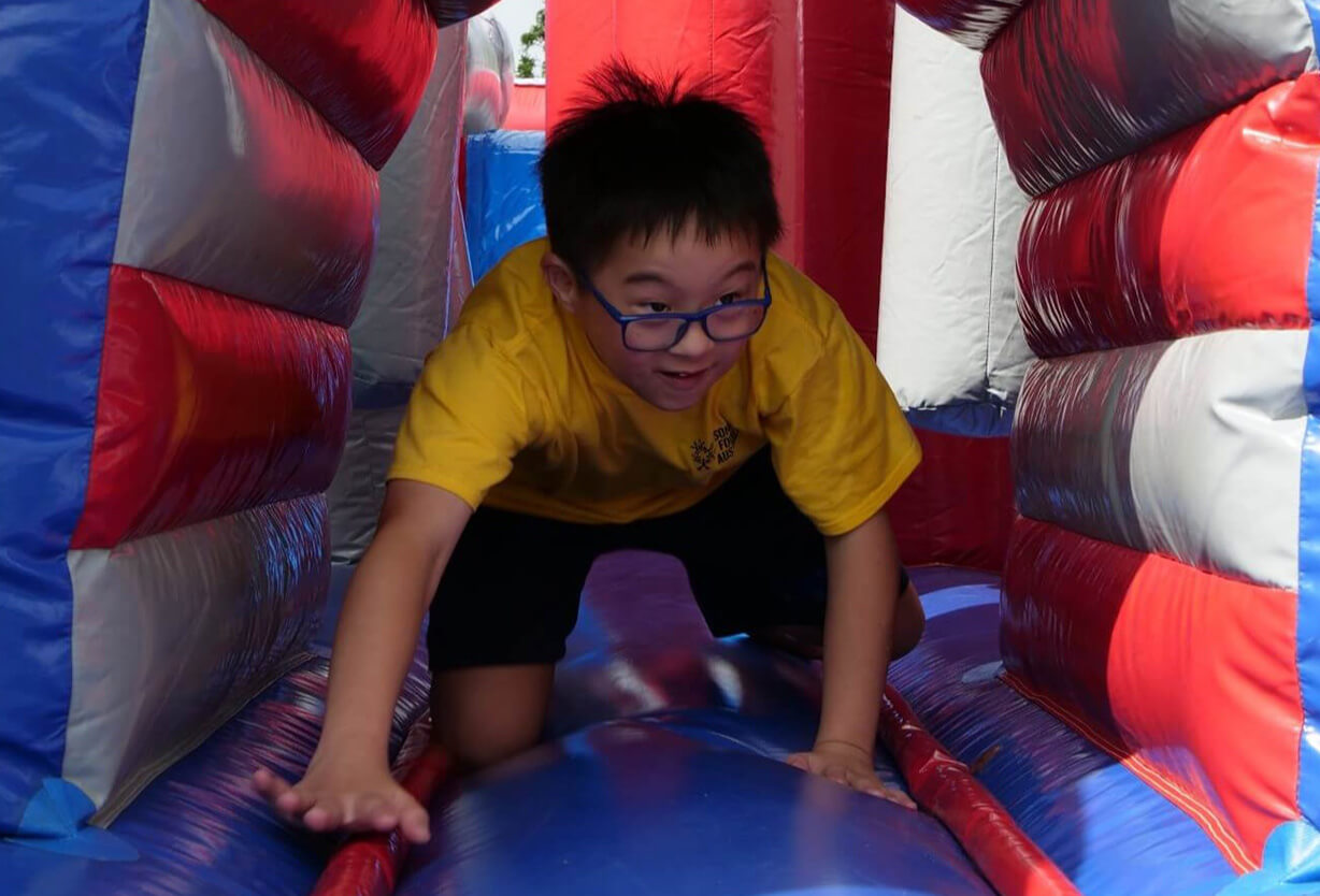 A child crawling through a tunnel on a jumping castle